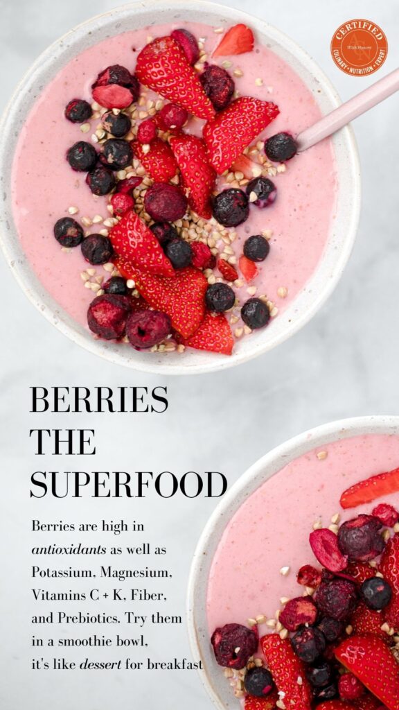 2 white bowls on grey marbled surface filled with pink smoothie liquid and topped with raspberries, blueberries, strawberries, blueberries and spoon sticking out; heart healthy